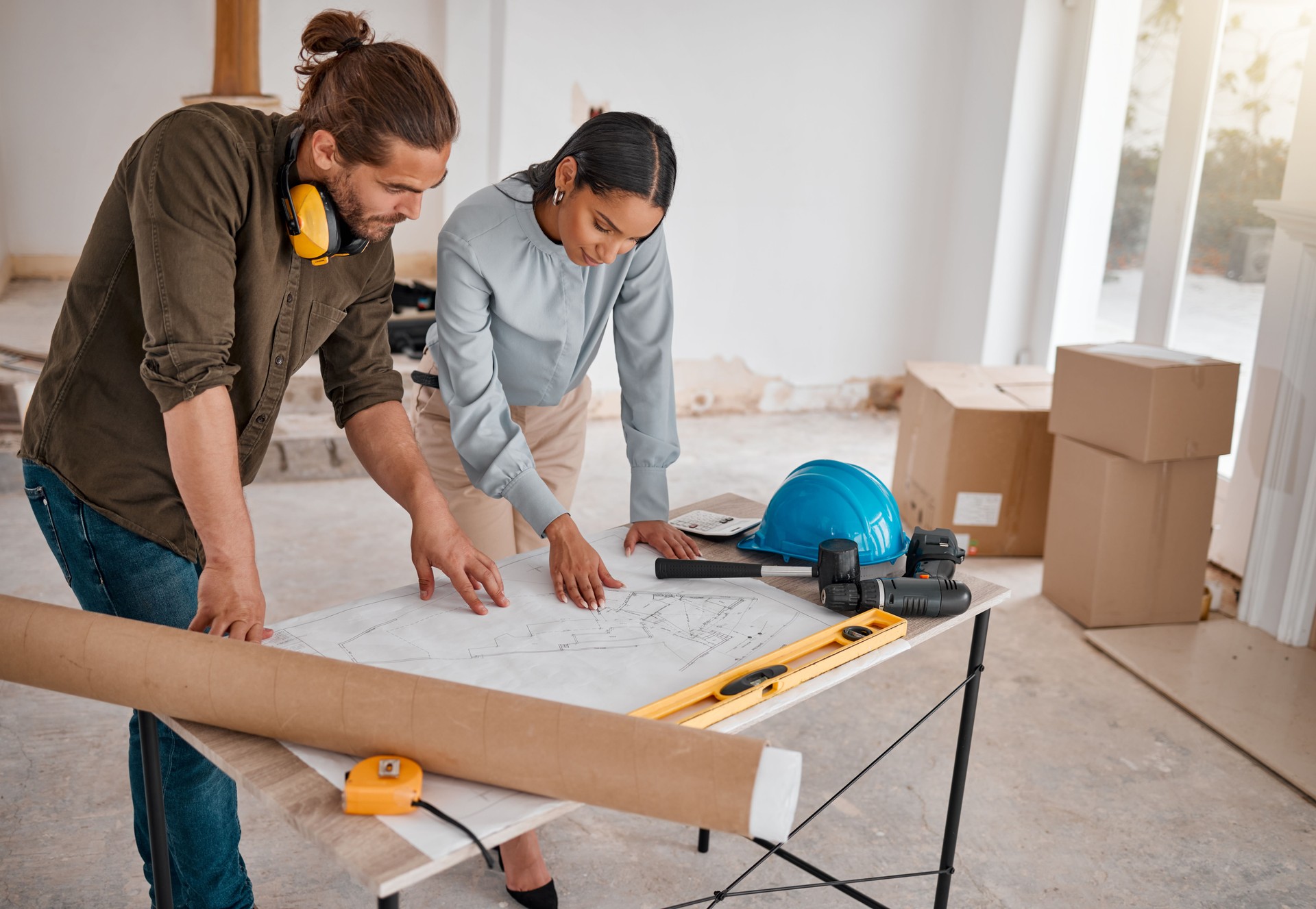 Shot of two young architects looking at building plans on site