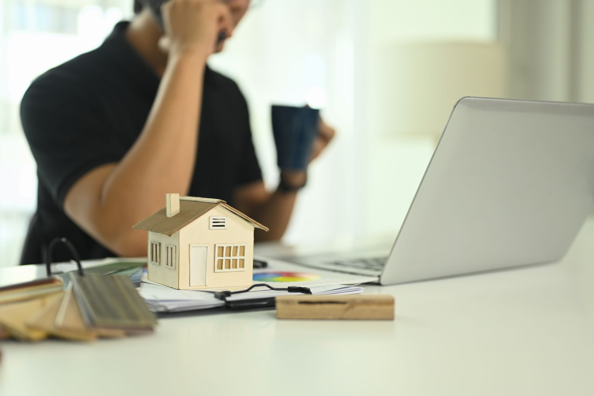 Small house model and color swatches on desk representing architectural design or real estate development